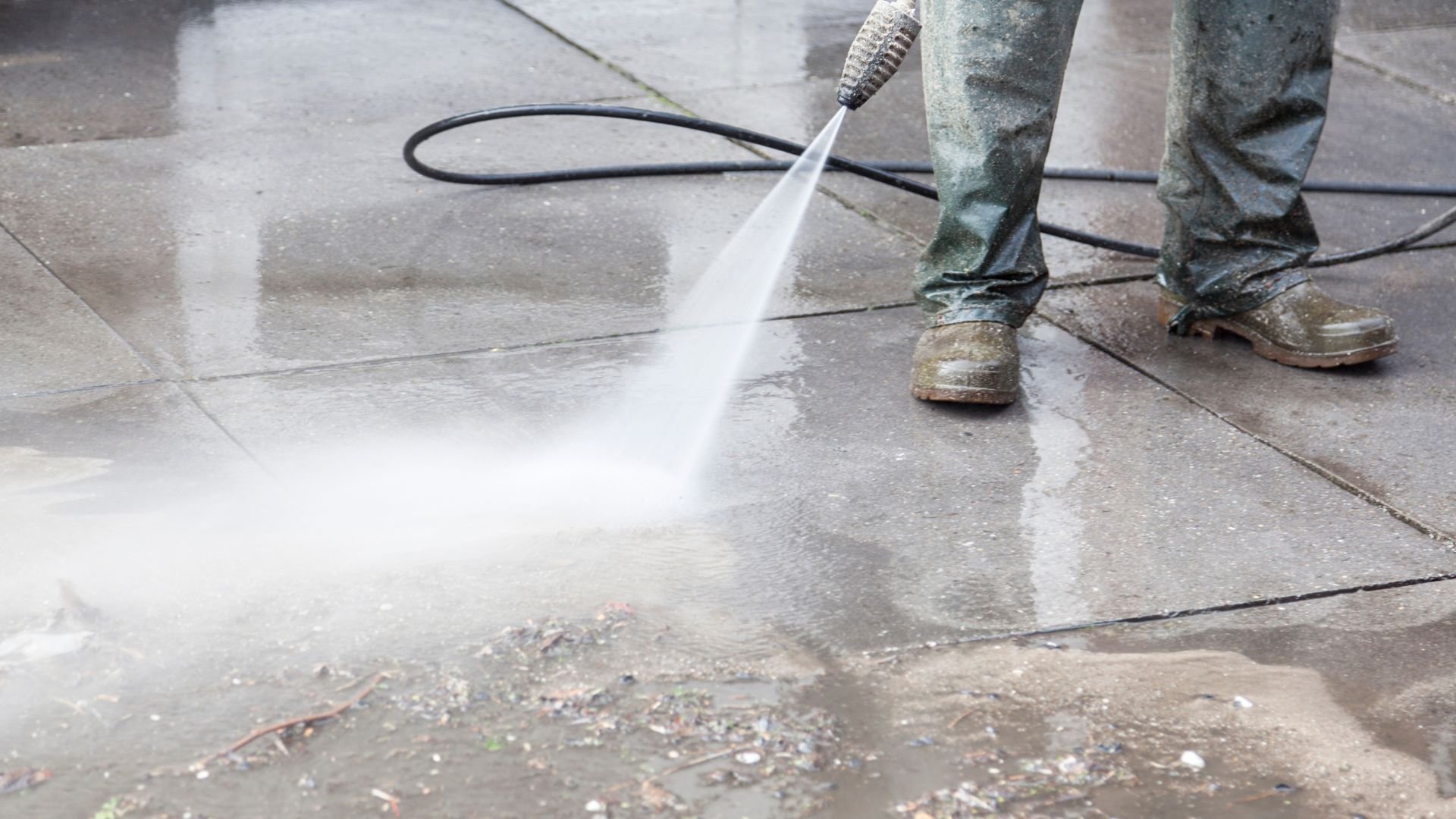 Pressure washer cleaning concrete surface with high-pressure water spray